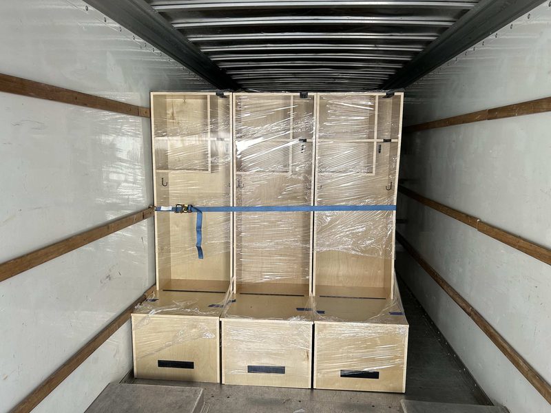 Three lockers stretch-wrapped and ratchet-strapped inside a box truck