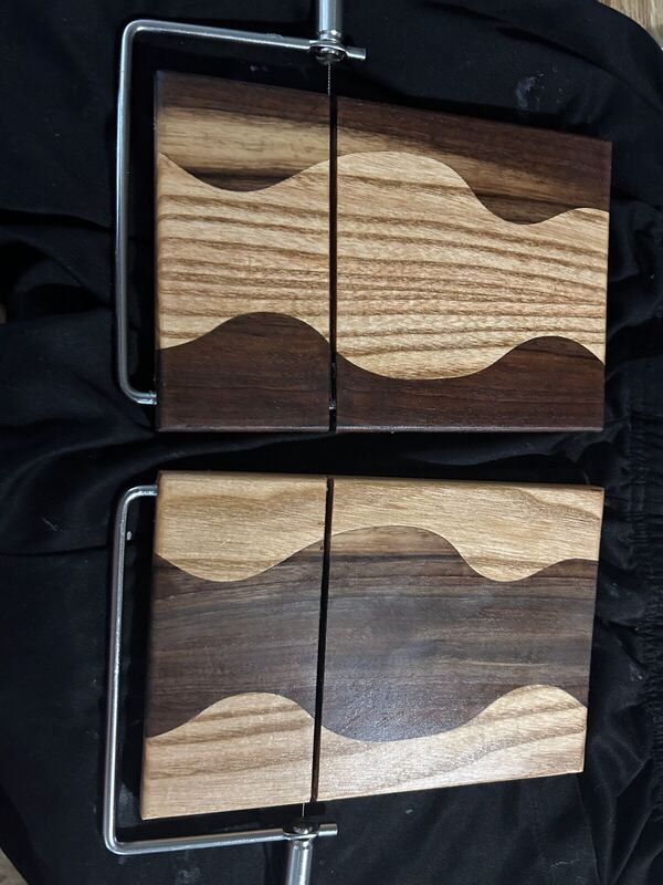 Two cheese boards with a wave pattern and wire slicers